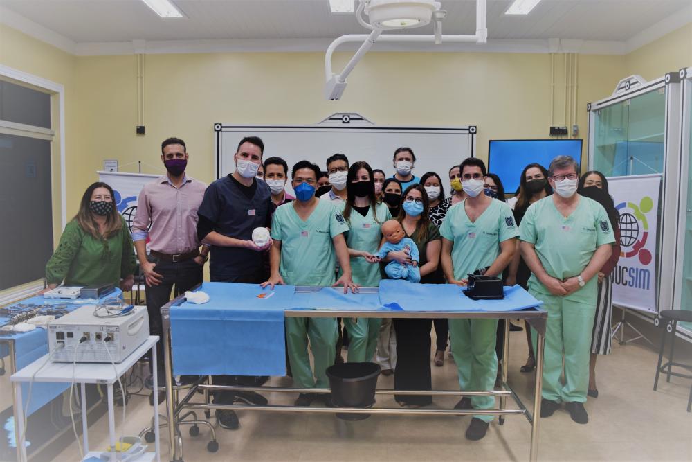 Equipe envolvida na cirurgia posa com o modelo híbrido e o molde em 3D do crânio da criança